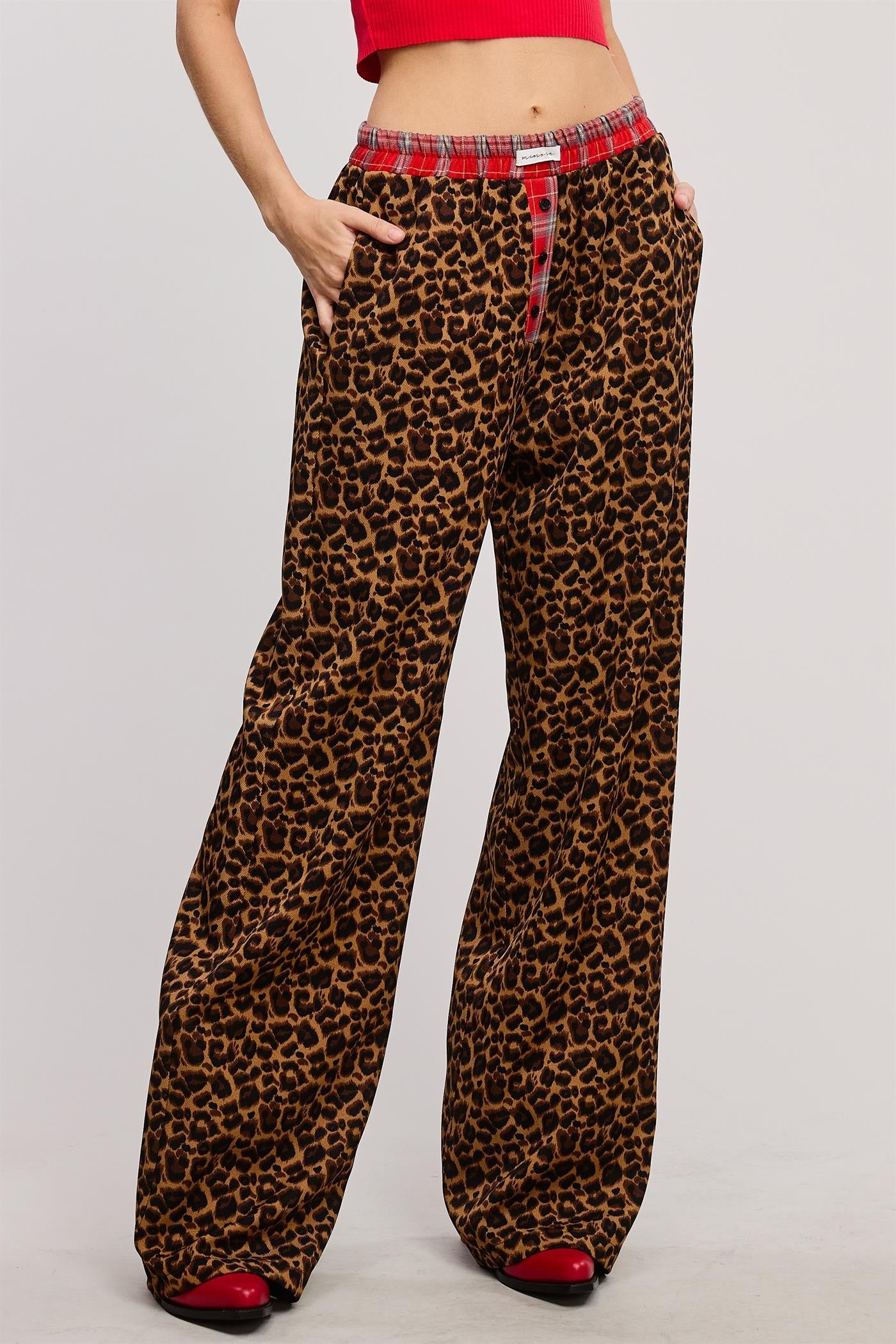 Bold and cozy, these leopard print lounge pants feature a relaxed, wide-leg fit with a contrasting red plaid elastic waistband and button fly detail. Made from soft, breathable fabric, these stylish pajama pants offer the perfect mix of comfort and statement-making fashion.
