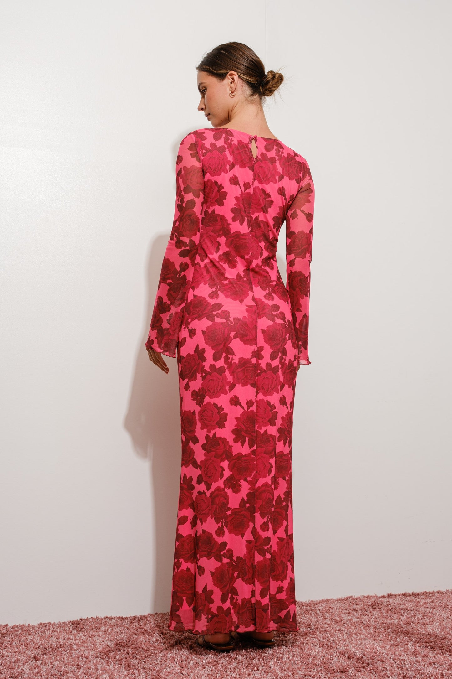Woman wearing a pink floral dress against a white background