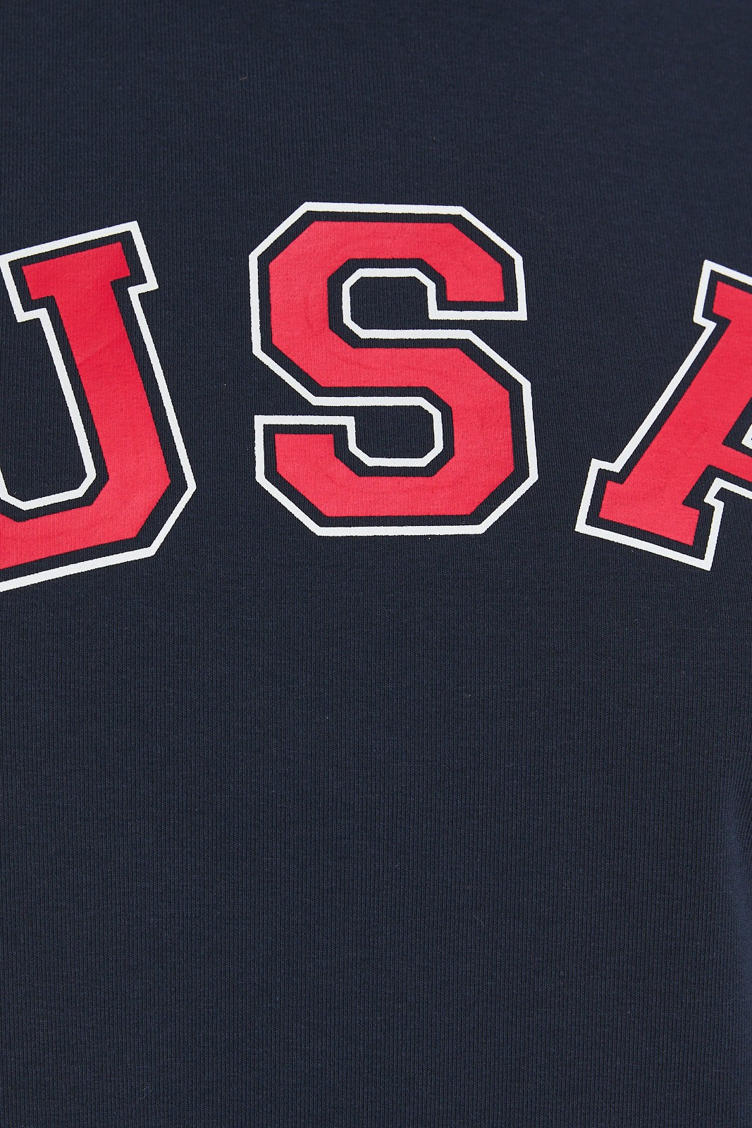 Close-up of a navy blue cropped t-shirt with bold red “USA” lettering outlined in white across the chest.