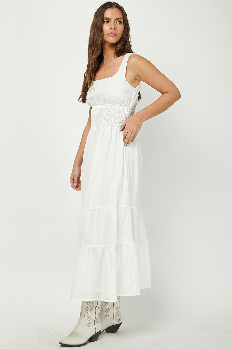 Woman wearing a white tiered maxi dress with a square neckline and smocked waist, paired with white cowboy boots. A breezy and elegant outfit perfect for summer, country-chic looks, or casual events.