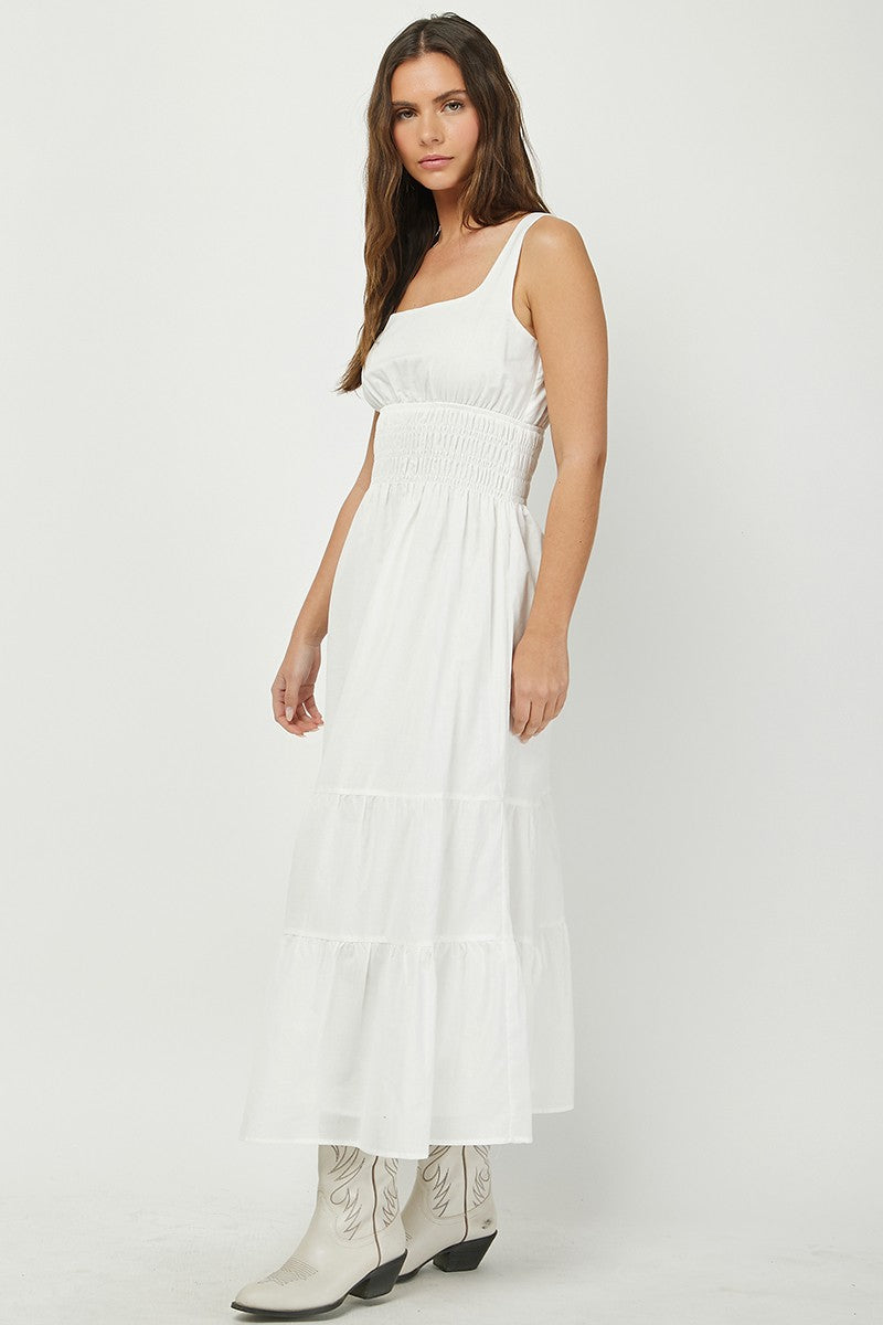 Woman wearing a white tiered maxi dress with a square neckline and smocked waist, paired with white cowboy boots. A breezy and elegant outfit perfect for summer, country-chic looks, or casual events.