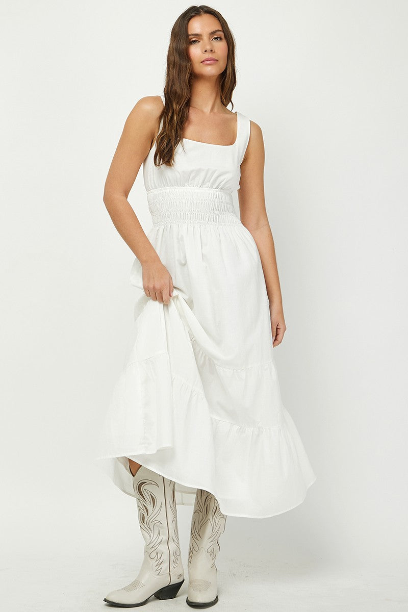 Woman wearing a white tiered maxi dress with a square neckline and smocked waist, paired with white cowboy boots. A breezy and elegant outfit perfect for summer, country-chic looks, or casual events.