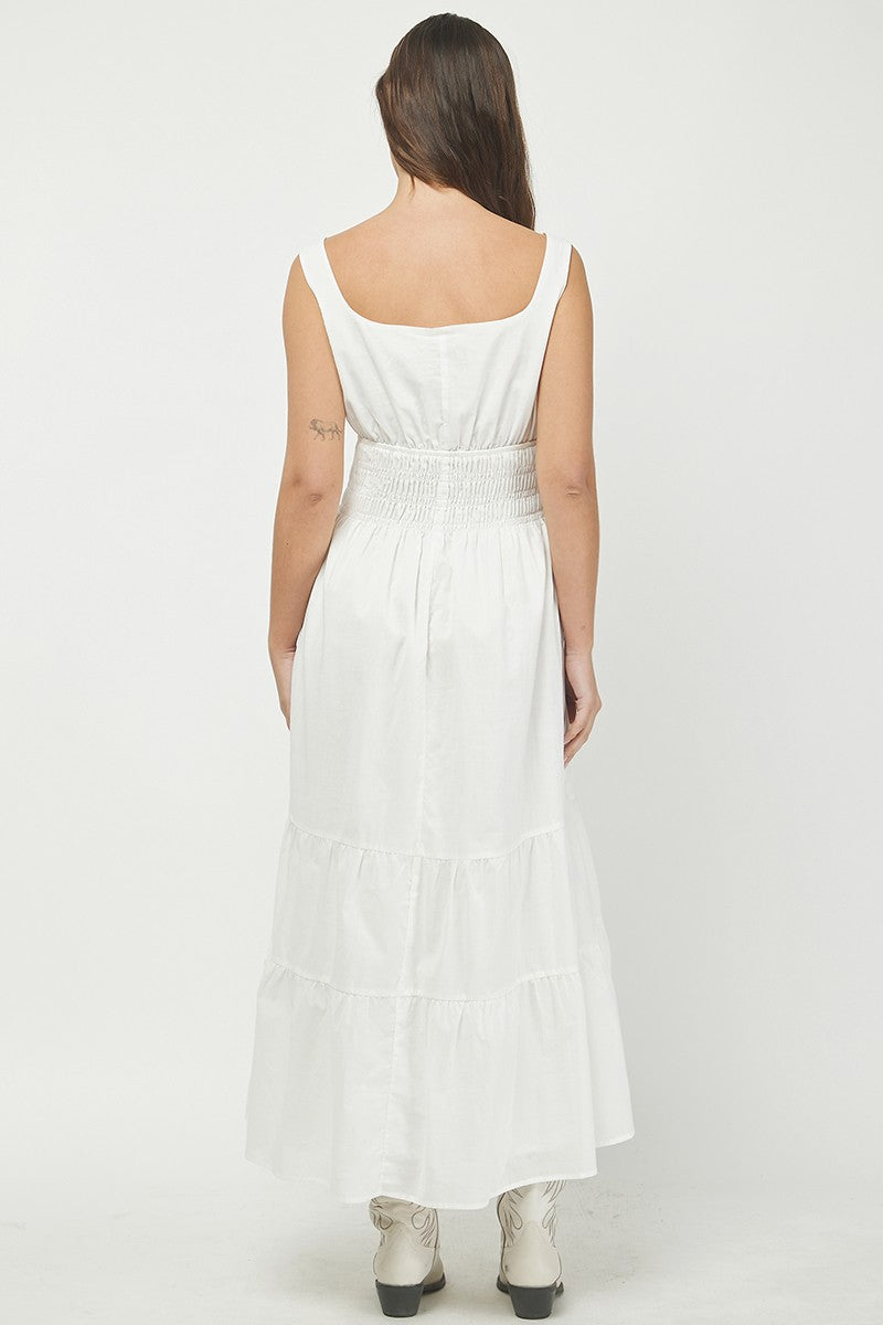 Woman wearing a white tiered maxi dress with a square neckline and smocked waist, paired with white cowboy boots. A breezy and elegant outfit perfect for summer, country-chic looks, or casual events.
