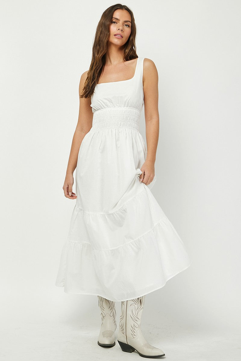 Woman wearing a white tiered maxi dress with a square neckline and smocked waist, paired with white cowboy boots. A breezy and elegant outfit perfect for summer, country-chic looks, or casual events.