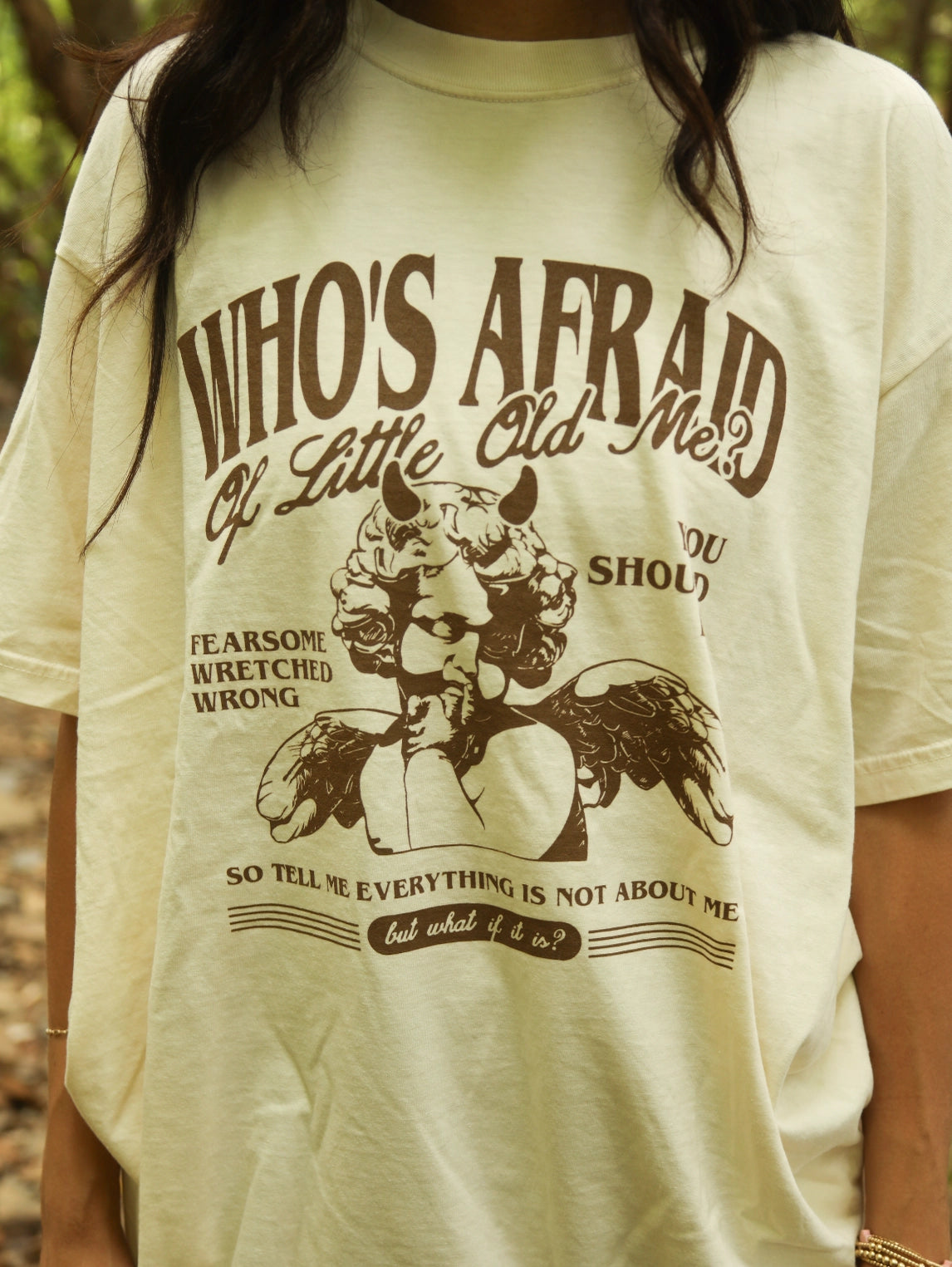 Beige t-shirt with graphic design and text worn by a person outdoors