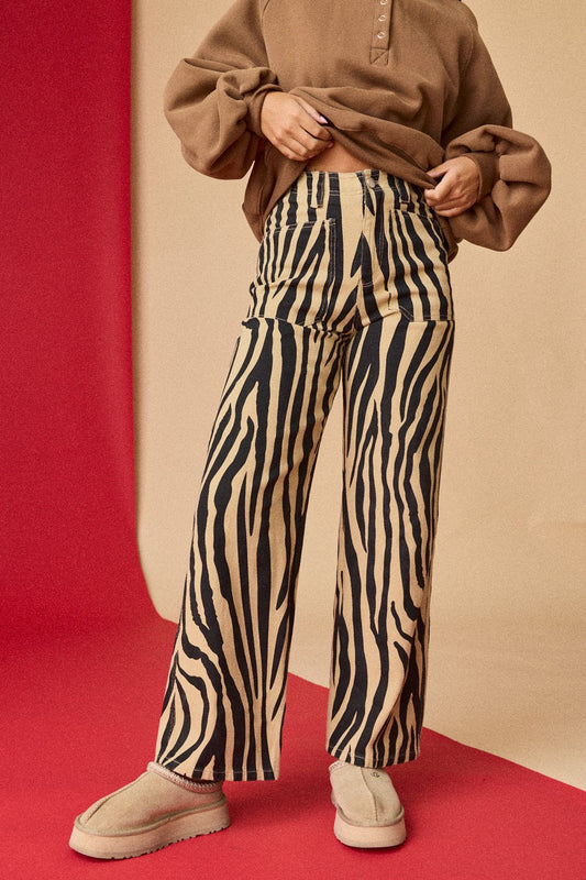 Person wearing zebra print pants and a brown top on a red and beige background