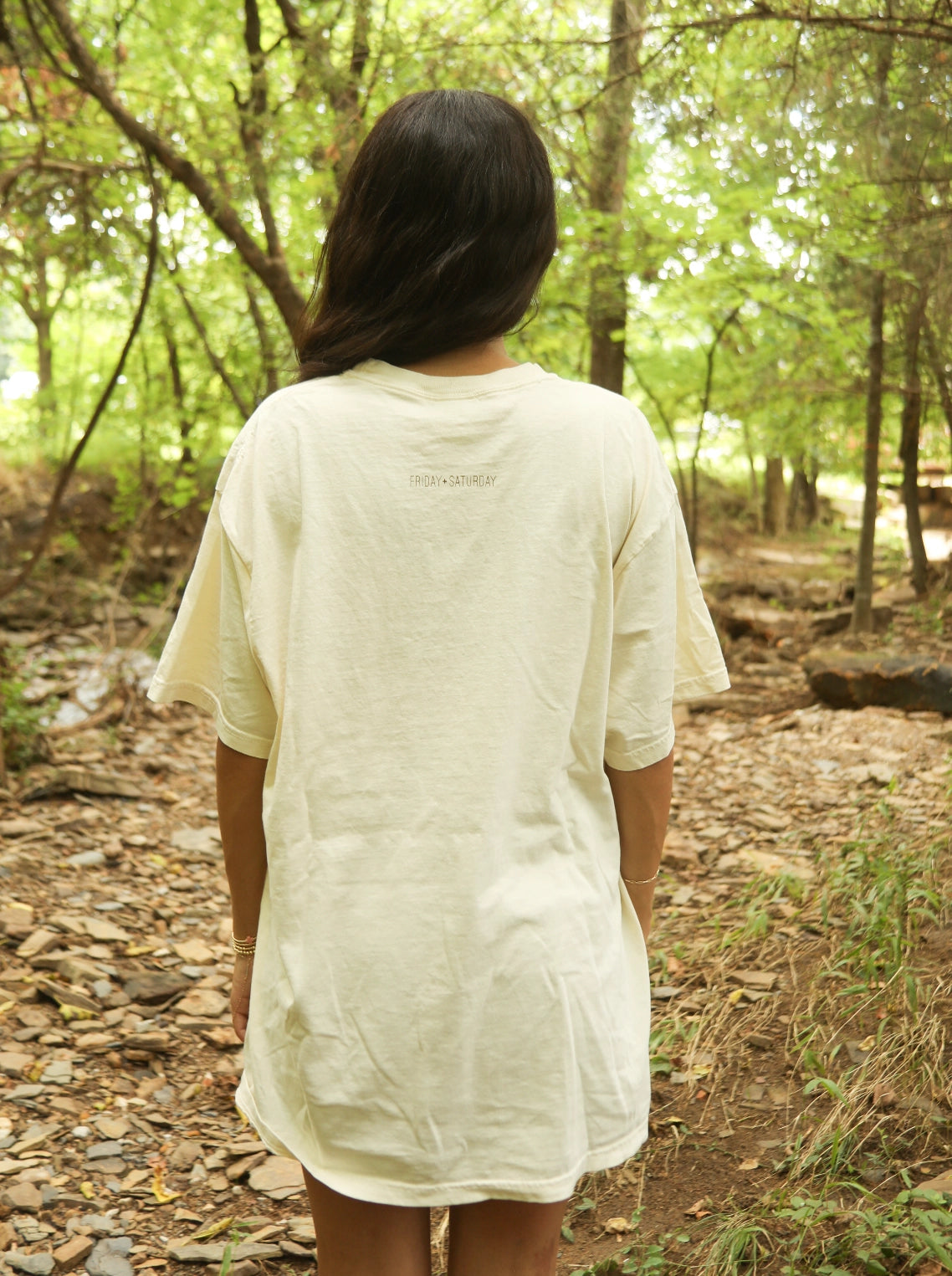 Person wearing a white oversized shirt in a forest setting