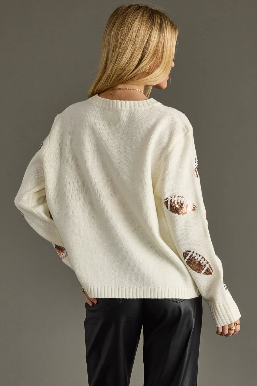 Back view of Women wearing a cream sweater with sequin footballs on the arms