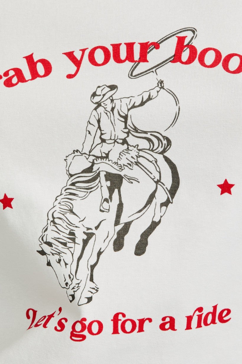 Up close shot of western-style graphic baby tee with grey sleeves and red cowboy text that reads “Grab your boots, let’s go for a ride”