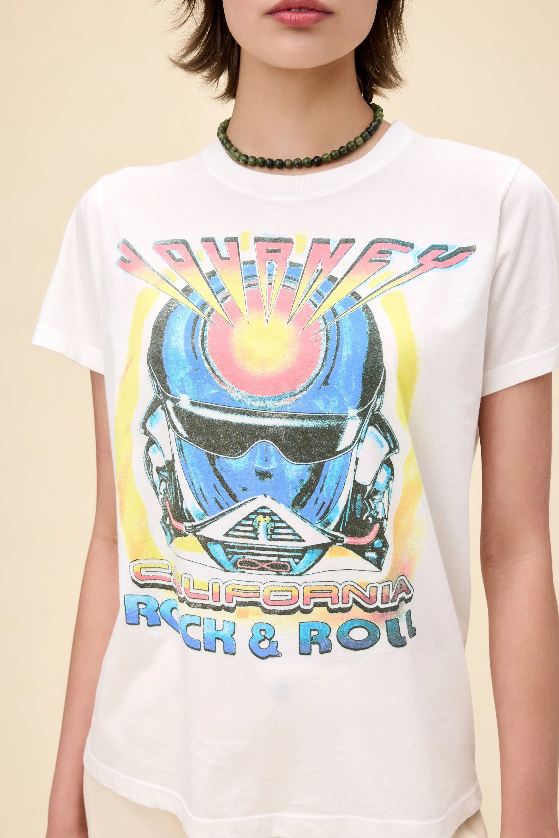 Vintage-inspired Journey California Rock & Roll graphic tee, featuring a bold retro helmet design on the front with colorful gradient lettering. The back showcases a 1983 Los Angeles concert graphic with palm trees and a sunset aesthetic. Designed in a relaxed fit, this lightweight tee is perfect for music lovers and casual streetwear.