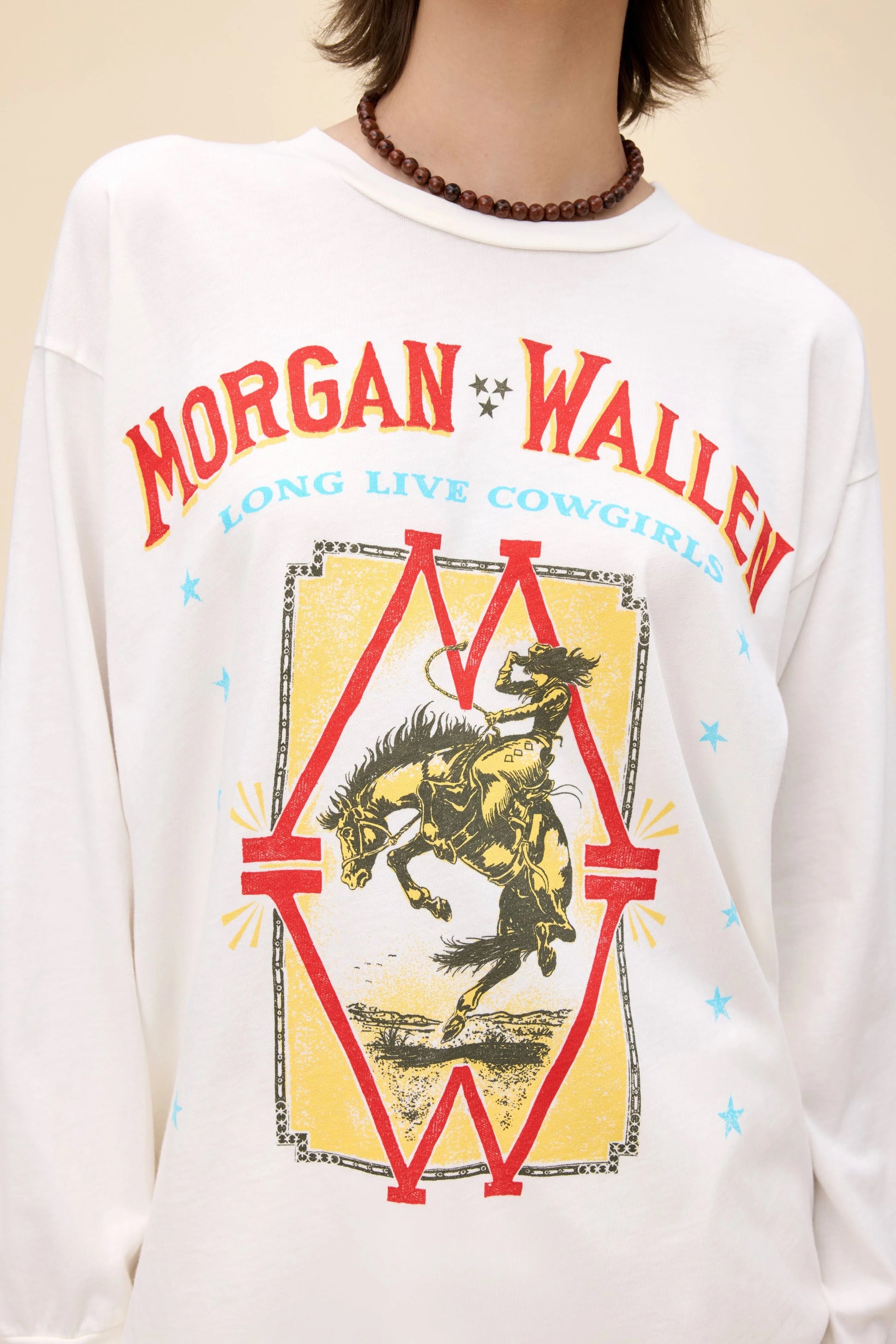 White Morgan Wallen Long Live Cowgirls graphic tee, featuring a vintage-inspired bronco riding print, bold red and blue lettering, and Western-style star details. Designed in a relaxed, oversized fit, this long-sleeve shirt is perfect for country music lovers and casual cowboy-inspired outfits.