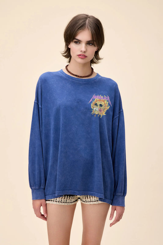 Front  view of a blue oversized long sleeve Metallica graphic tee featuring a flaming flower skull design on the front and back, worn with crochet shorts.