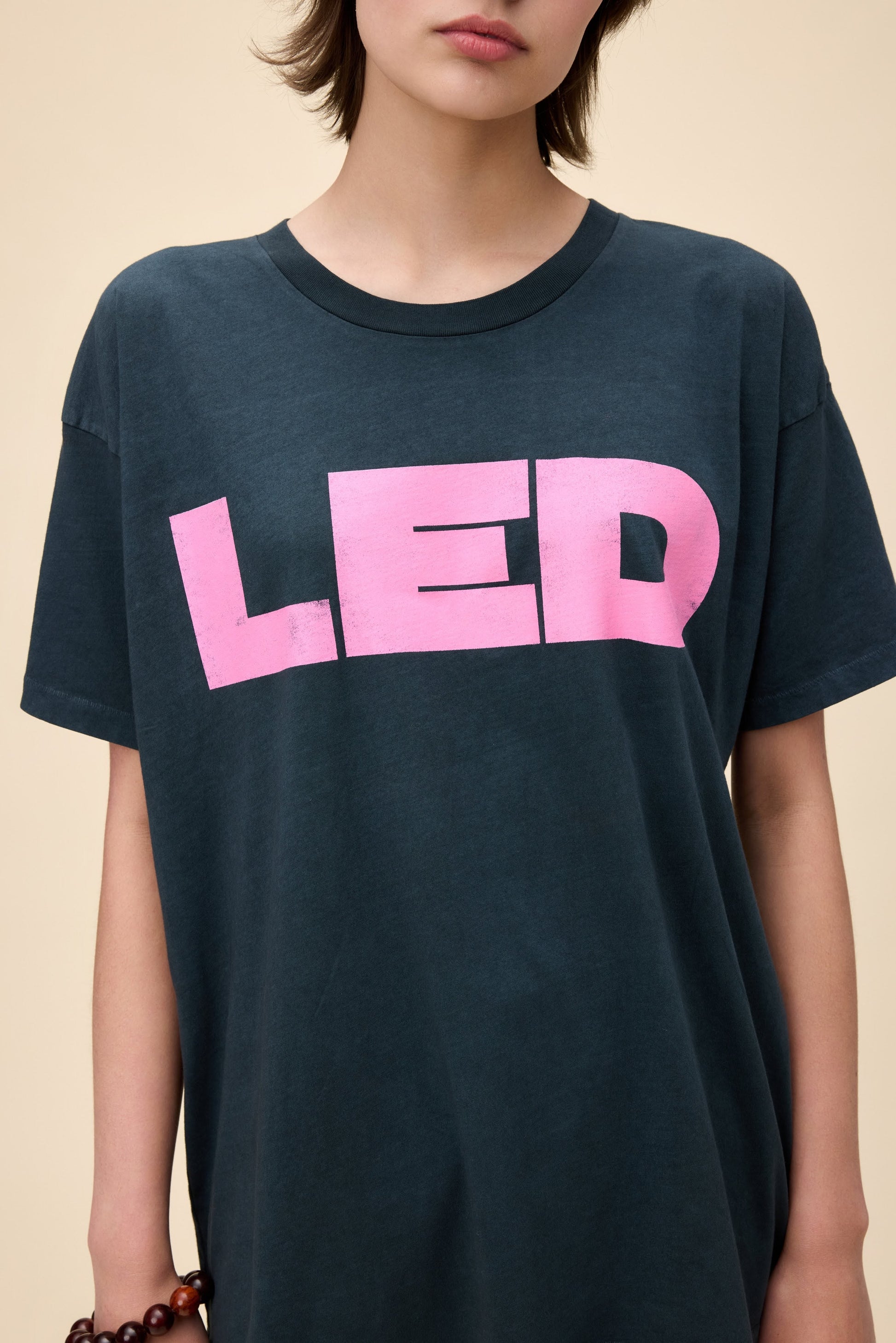Model wearing a vintage-style Led Zeppelin oversized black t-shirt with pink "LED" print on the front.