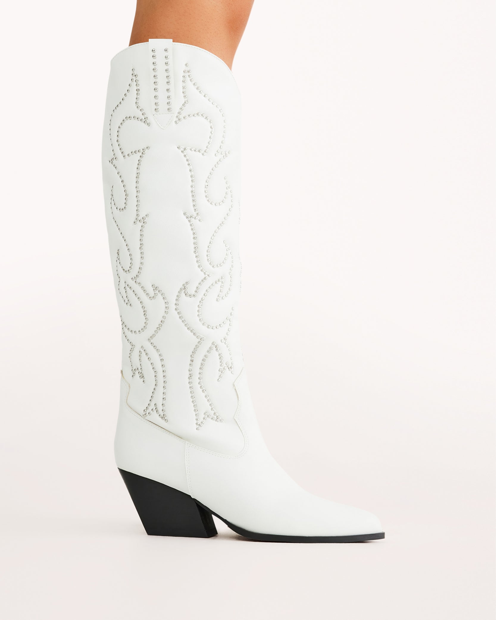 Chic and bold, these white western knee-high boots feature classic cowboy stitching with silver stud embellishments, a pointed toe, and a stacked angled heel. Perfect for country concerts, bachelorette parties, festivals, or trendy street style looks.