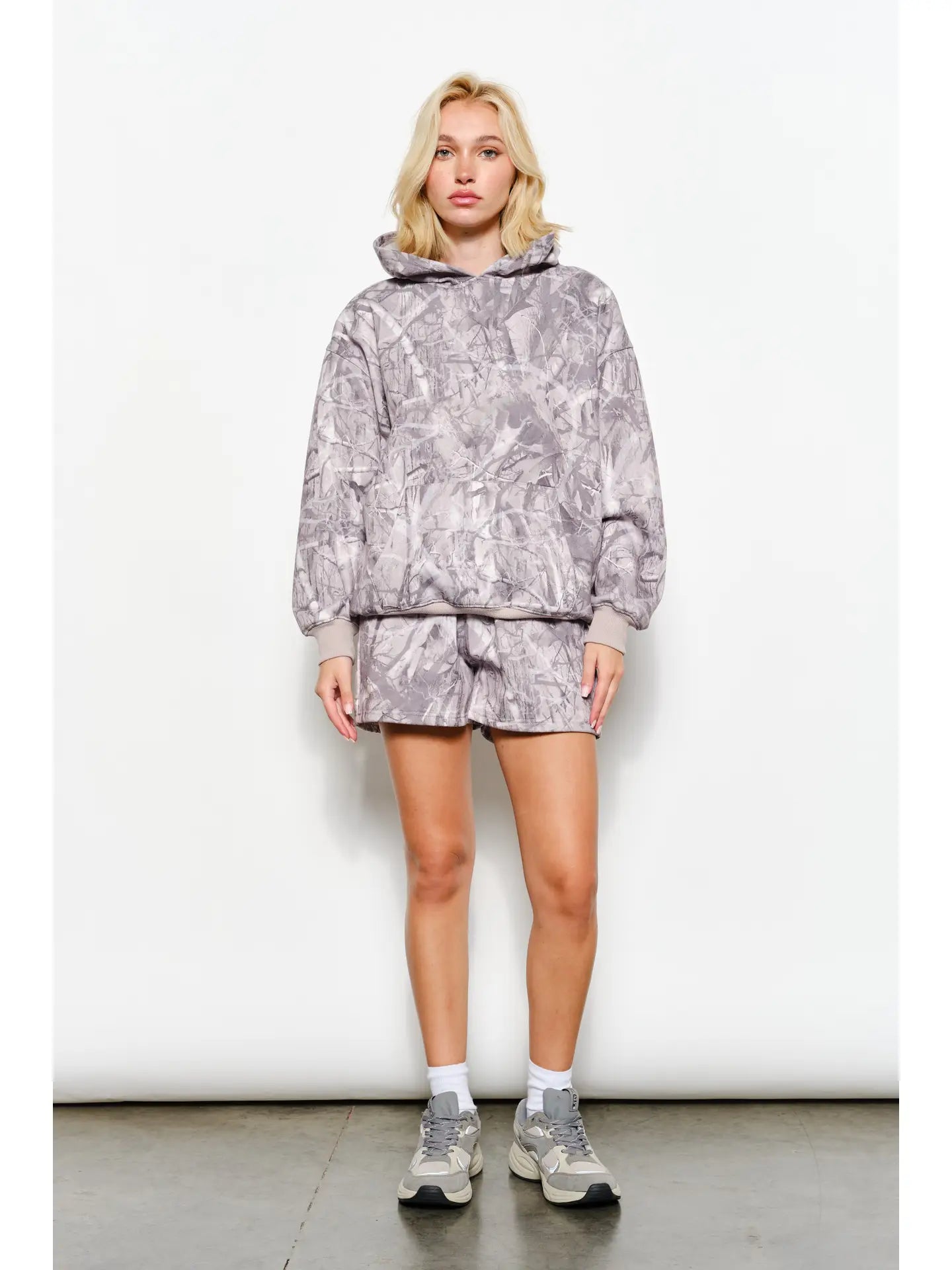 Person wearing a gray tie-dye hoodie and shorts set against a white background