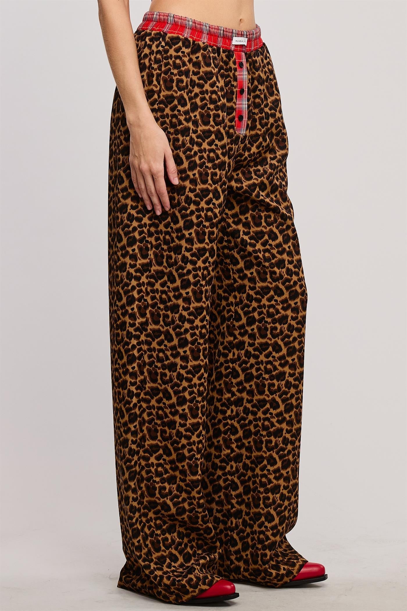 Bold and cozy, these leopard print lounge pants feature a relaxed, wide-leg fit with a contrasting red plaid elastic waistband and button fly detail. Made from soft, breathable fabric, these stylish pajama pants offer the perfect mix of comfort and statement-making fashion.