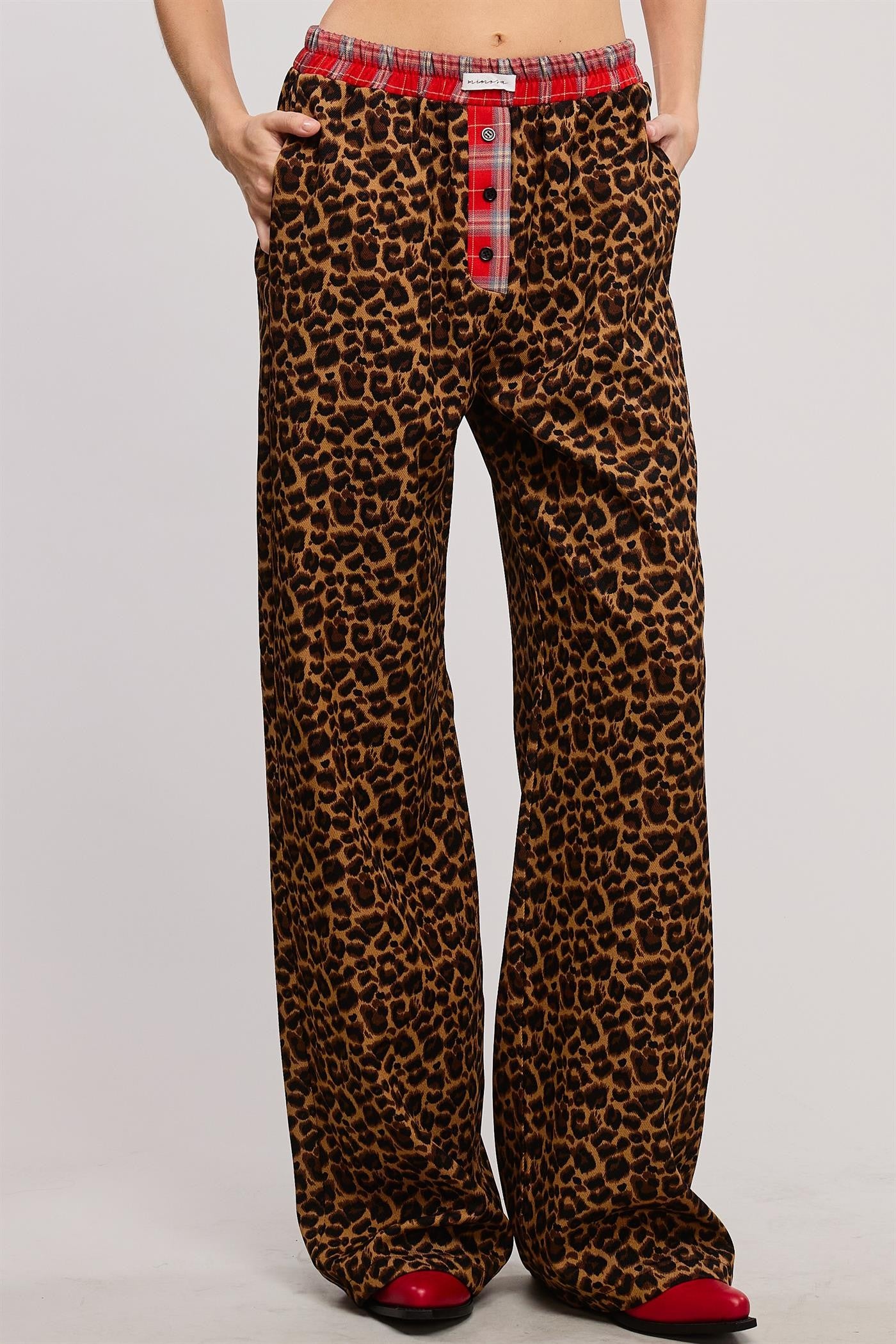 Bold and cozy, these leopard print lounge pants feature a relaxed, wide-leg fit with a contrasting red plaid elastic waistband and button fly detail. Made from soft, breathable fabric, these stylish pajama pants offer the perfect mix of comfort and statement-making fashion.