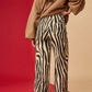 Person wearing zebra print pants and a beige sweater on a red and beige background