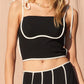 Stylish and modern, this black cropped tank top features contrast white piping, a square neckline, and adjustable tie straps for a customizable fit. Perfect for pairing with matching skirts, jeans, or shorts for a chic, elevated look.