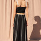 Stylish and modern, this black cropped tank top features contrast white piping, a square neckline, and adjustable tie straps for a customizable fit. Perfect for pairing with matching skirts, jeans, or shorts for a chic, elevated look.