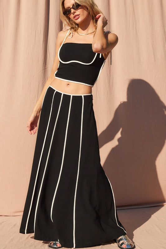 Chic and modern, this black maxi skirt features contrast white vertical piping for a bold, elongating effect. Designed with a flowy silhouette, this skirt combines effortless movement with sleek, statement style — perfect for nights out, vacations, or elevated casual looks.