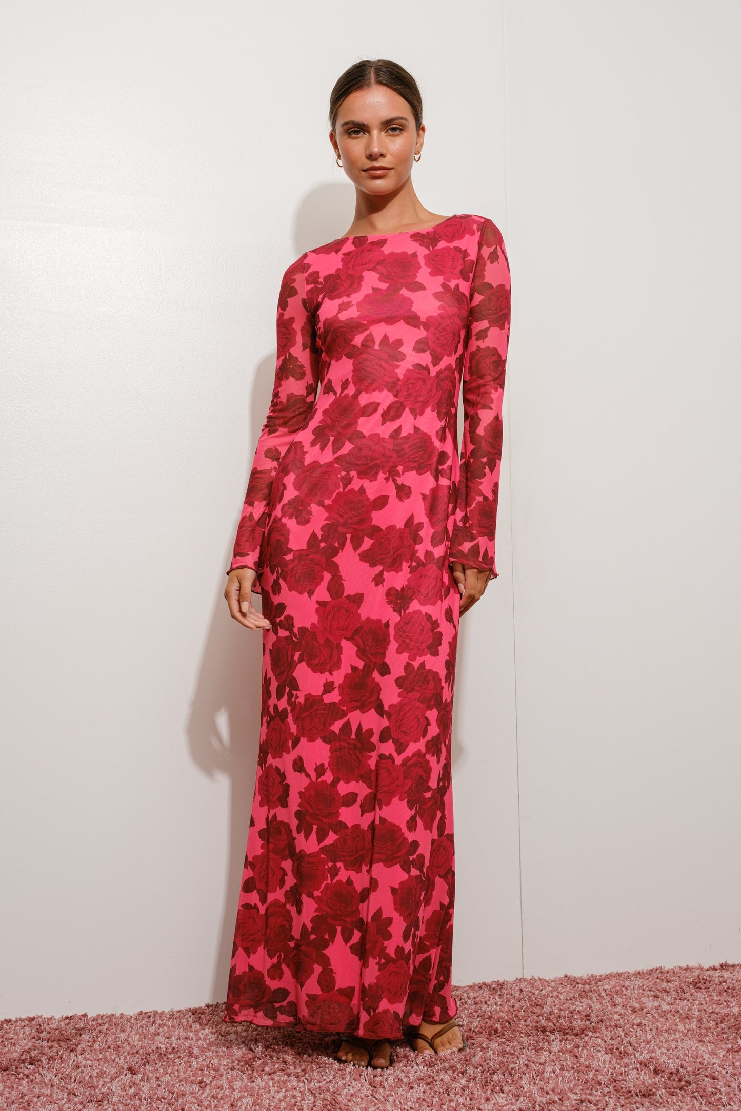 Model wearing a pink floral dress against a white background