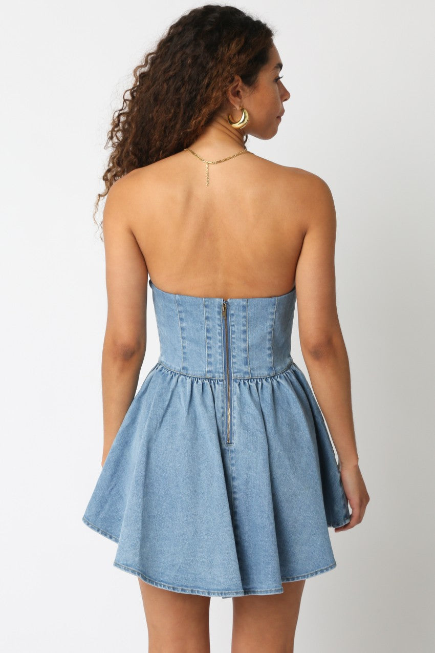 Back view of the denim mini dress showing a center zipper closure and flared hem.