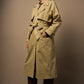Woman wearing a light green trench coat against a plain background