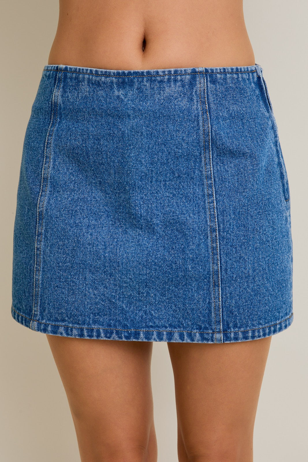 Blue denim skirt worn by a person on a plain background