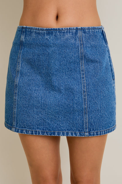Blue denim skirt worn by a person on a plain background