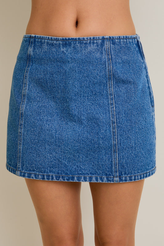 Blue denim skirt worn by a person on a plain background