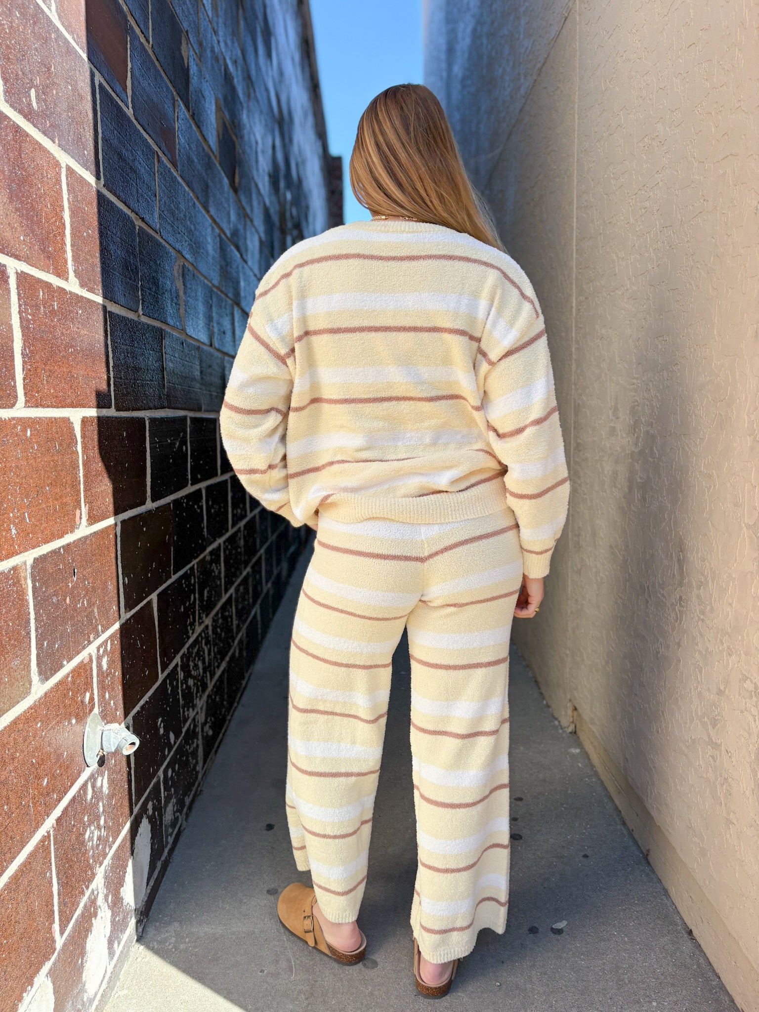 Person wearing a striped outfit walking between two walls.