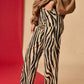 Person wearing zebra print pants and a brown sweater on a red and beige background