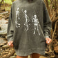 Person wearing a gray sweatshirt with skeleton designs in a forest setting