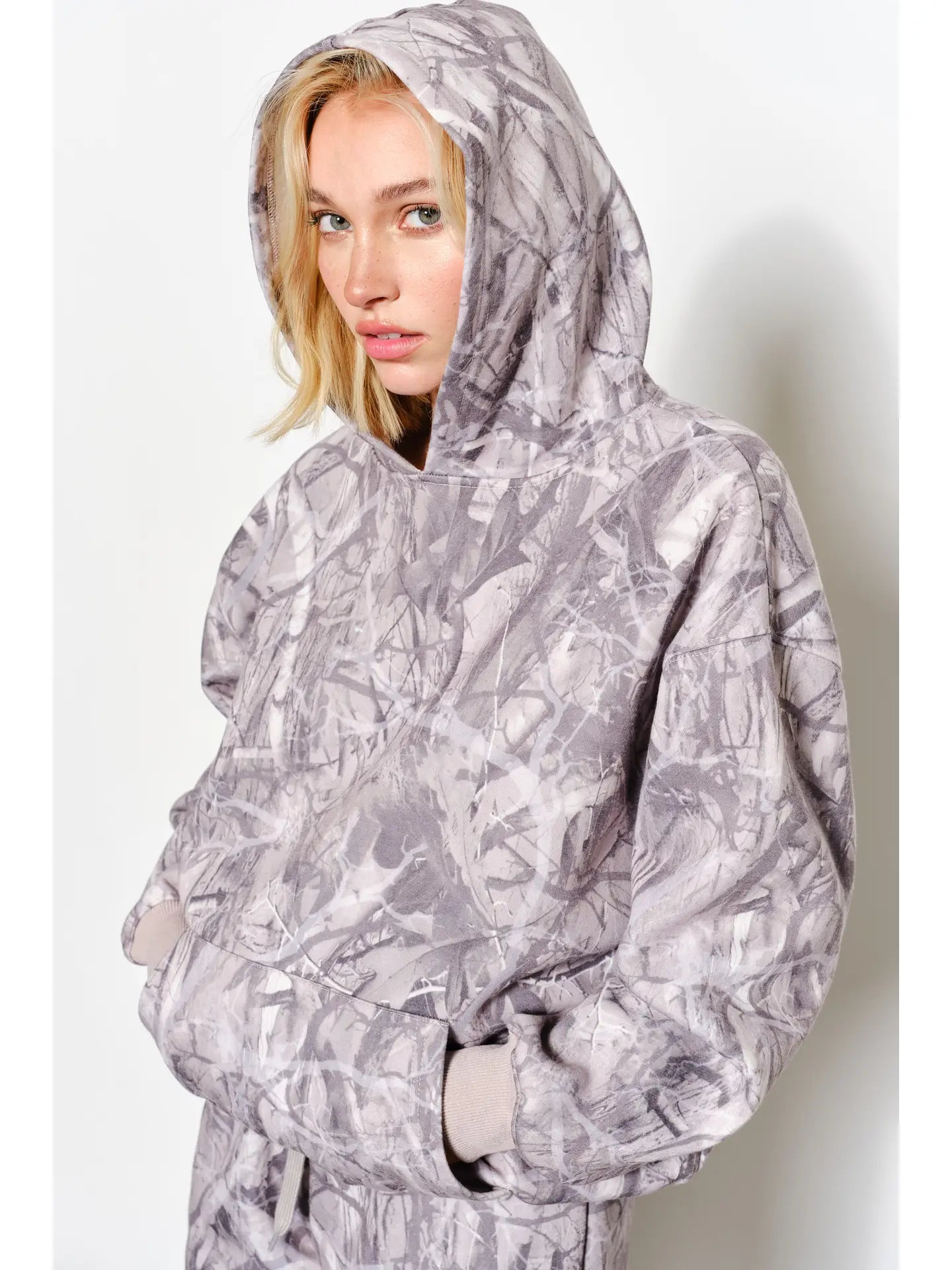 Person wearing a gray camouflage-patterned poncho against a white background