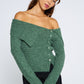 Woman wearing a green off-shoulder sweater against a white background