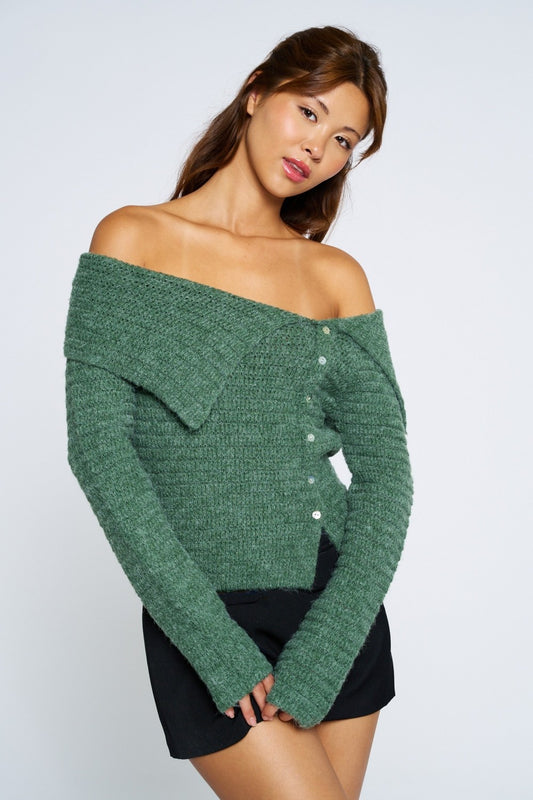 Woman wearing a green off-shoulder sweater against a white background