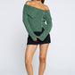 Woman wearing a green off-shoulder sweater and black skirt on a white background