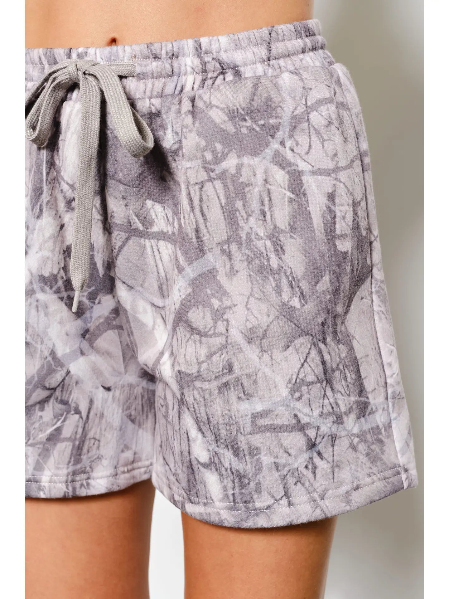 Gray patterned shorts worn by a person on a neutral background