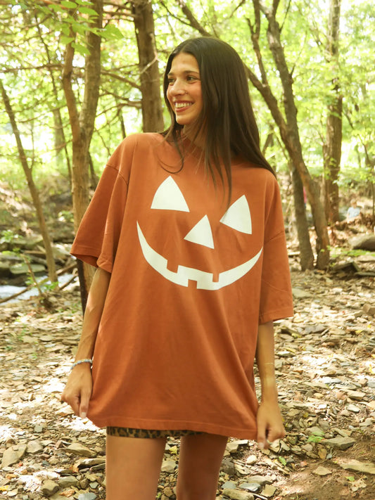 Woman wearing a pumpkin face t-shirt in a forest setting