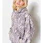 Person wearing a gray camouflage hoodie against a white background