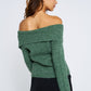 Woman wearing a green off-shoulder sweater and black skirt on a white background