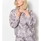 Woman wearing a gray patterned hoodie and shorts set against a white background