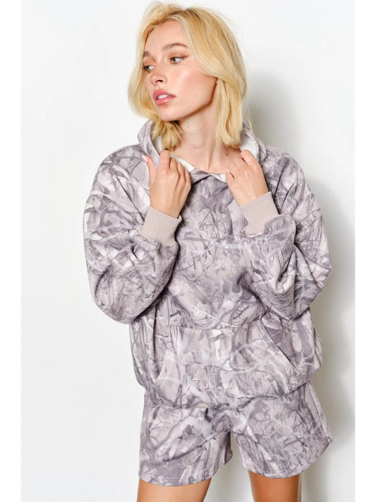 Woman wearing a gray patterned hoodie and shorts set against a white background