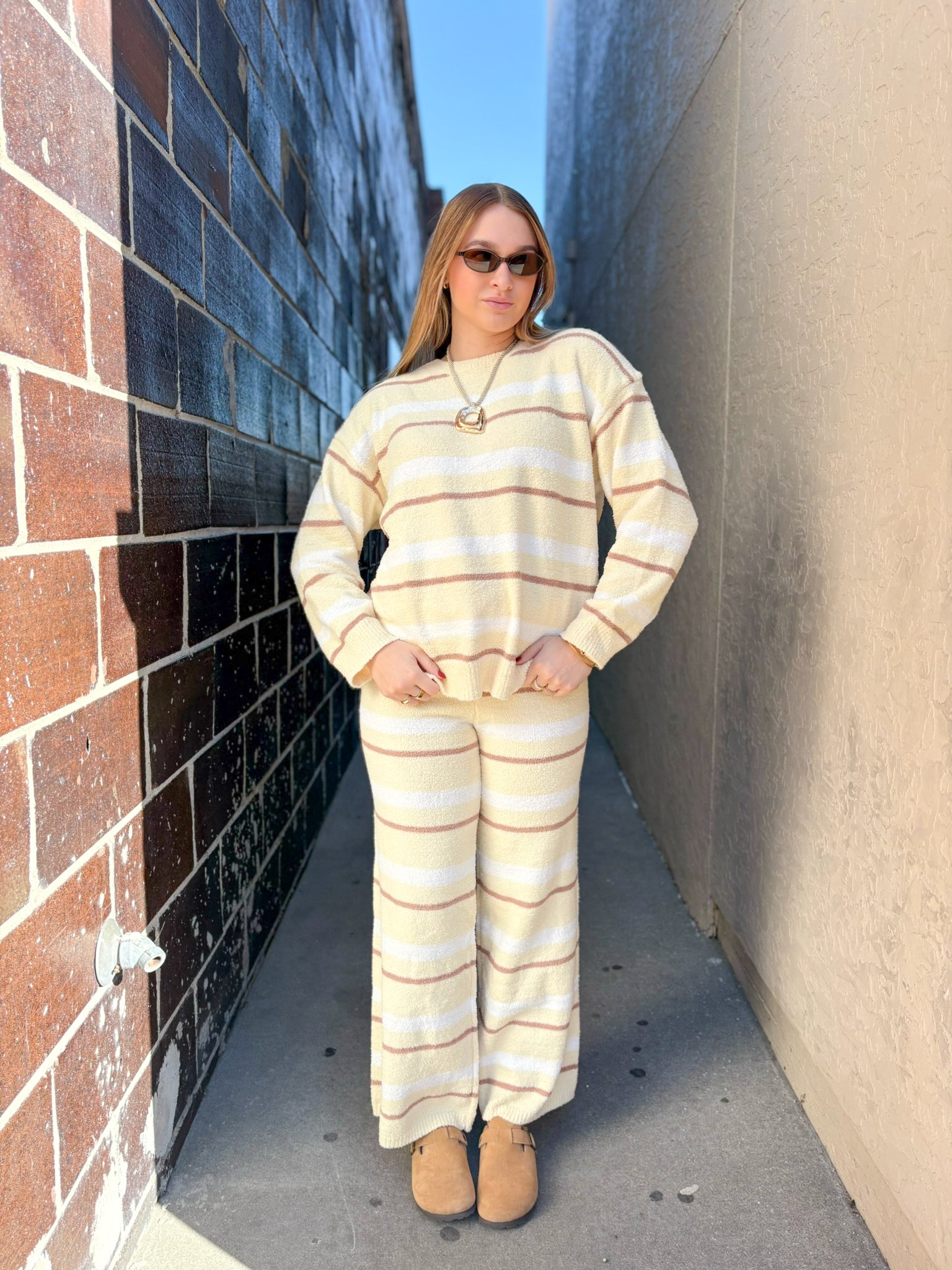 Woman wearing a striped outfit standing in a narrow alleyway.