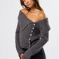 Woman wearing a gray off-shoulder sweater with buttons on a white background