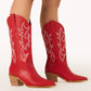 Red women’s cowboy boots, they are a mid calf boot with off white western stitching and a tan heel