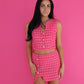 Woman wearing a pink checkered dress against a pink background