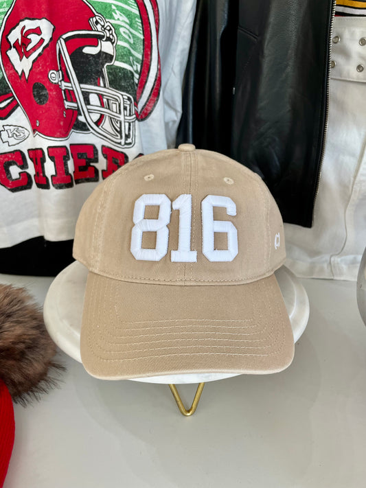 Beige cap with '816' on a white surface with a blurred background