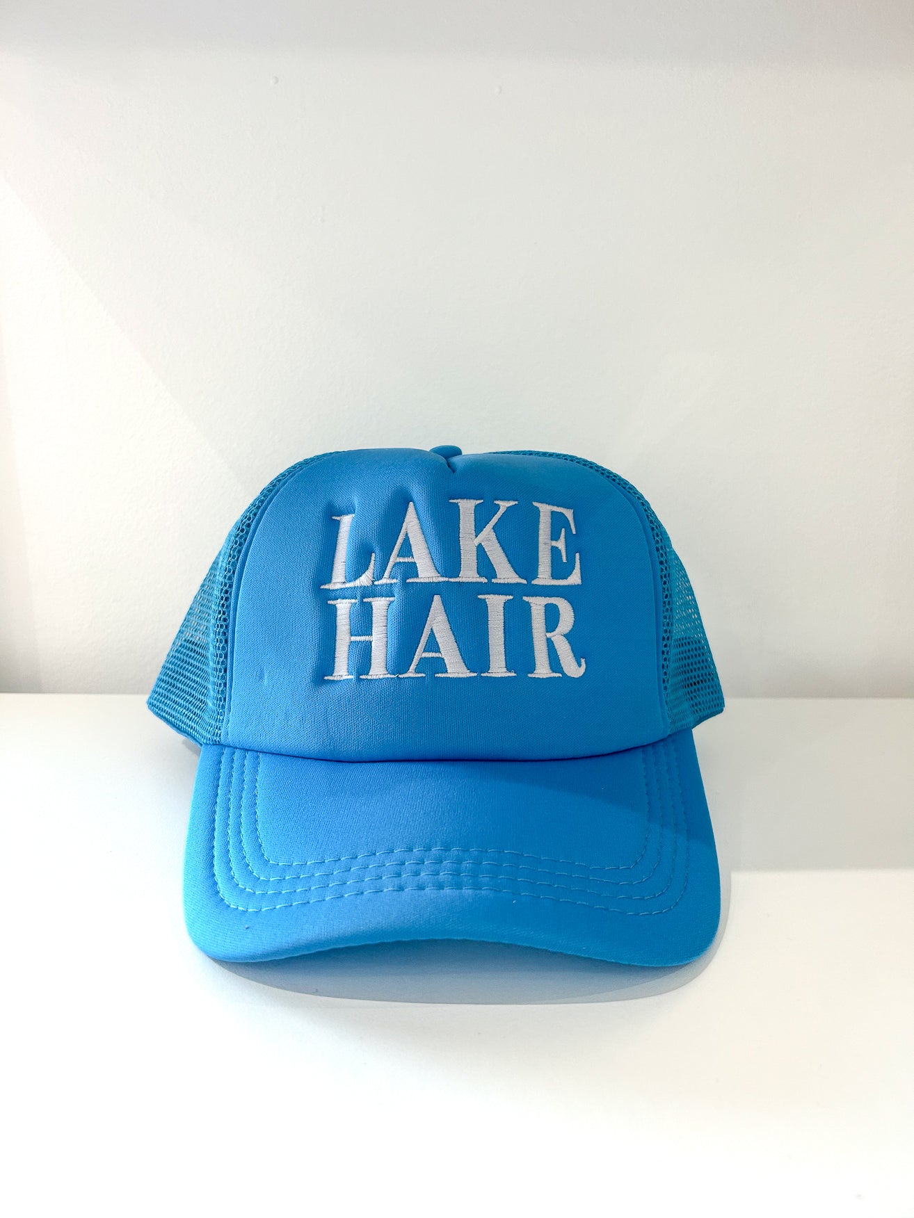 Aqua blue trucker hat with "Lake Hair" embroidered on the front